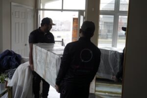 Moving ASAP crew carrying wrapped furniture into a home